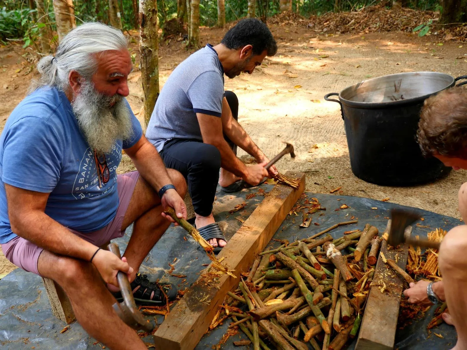 Guests learning to prepare ayahuasca, pounding the vine to open its fibers.